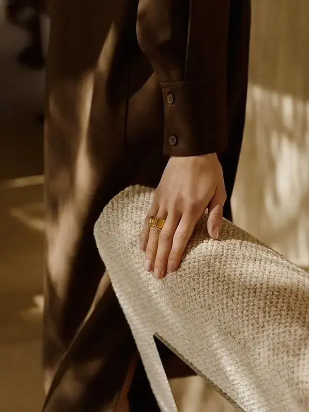 Hand with a gold ring holding a woven bag