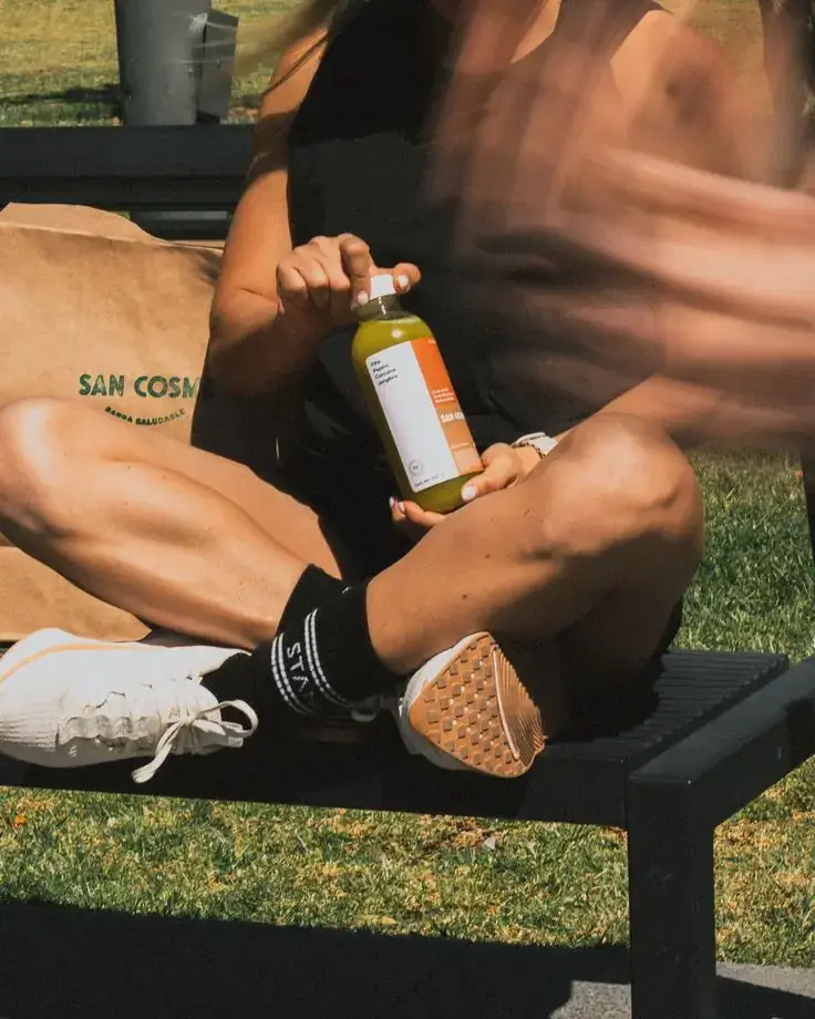 Bottled cold-pressed health drink held outdoors