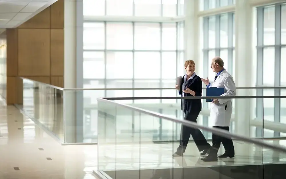 Hospital leader and doctor talking on a glass walkway