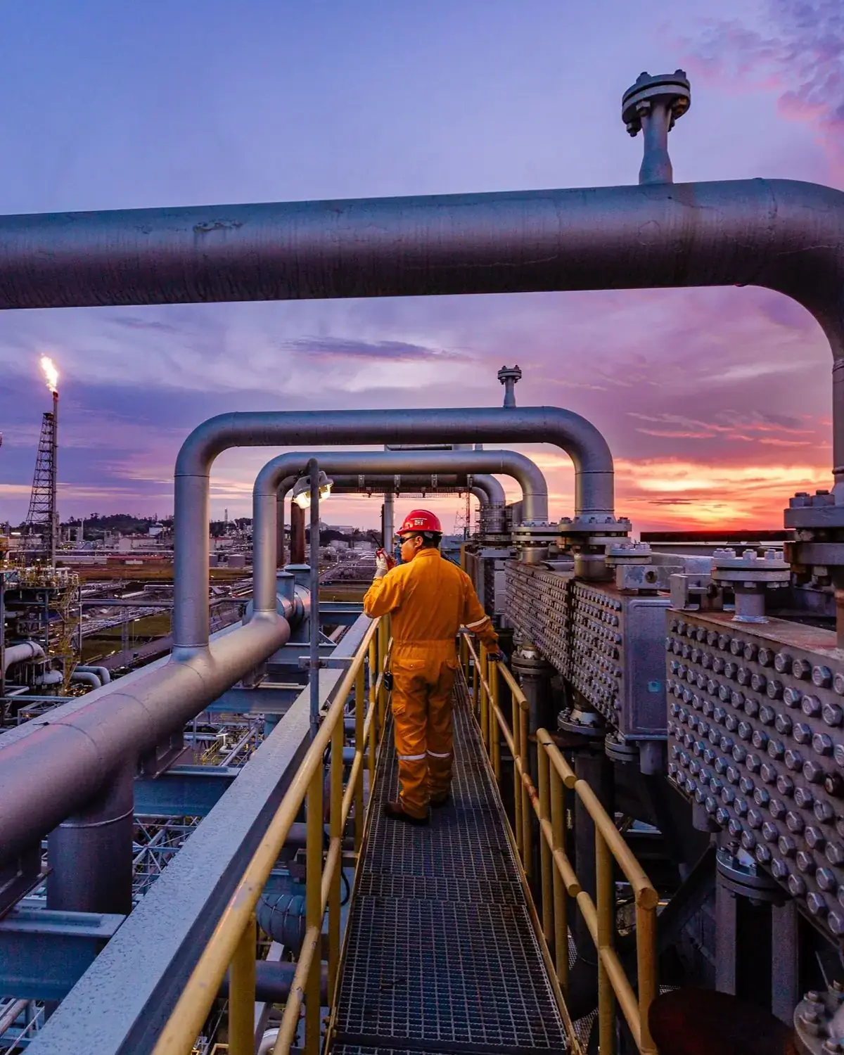 Engineer on a walkway at an industrial plant at dusk