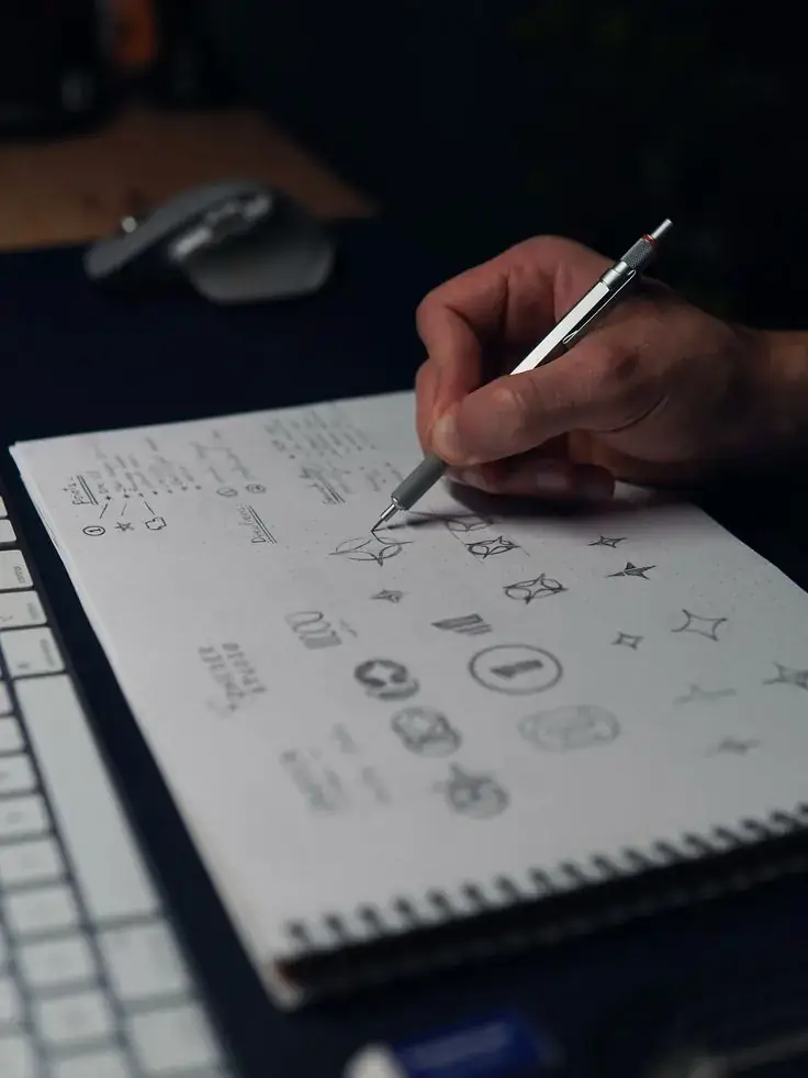 Designer sketching logo concepts in a notebook