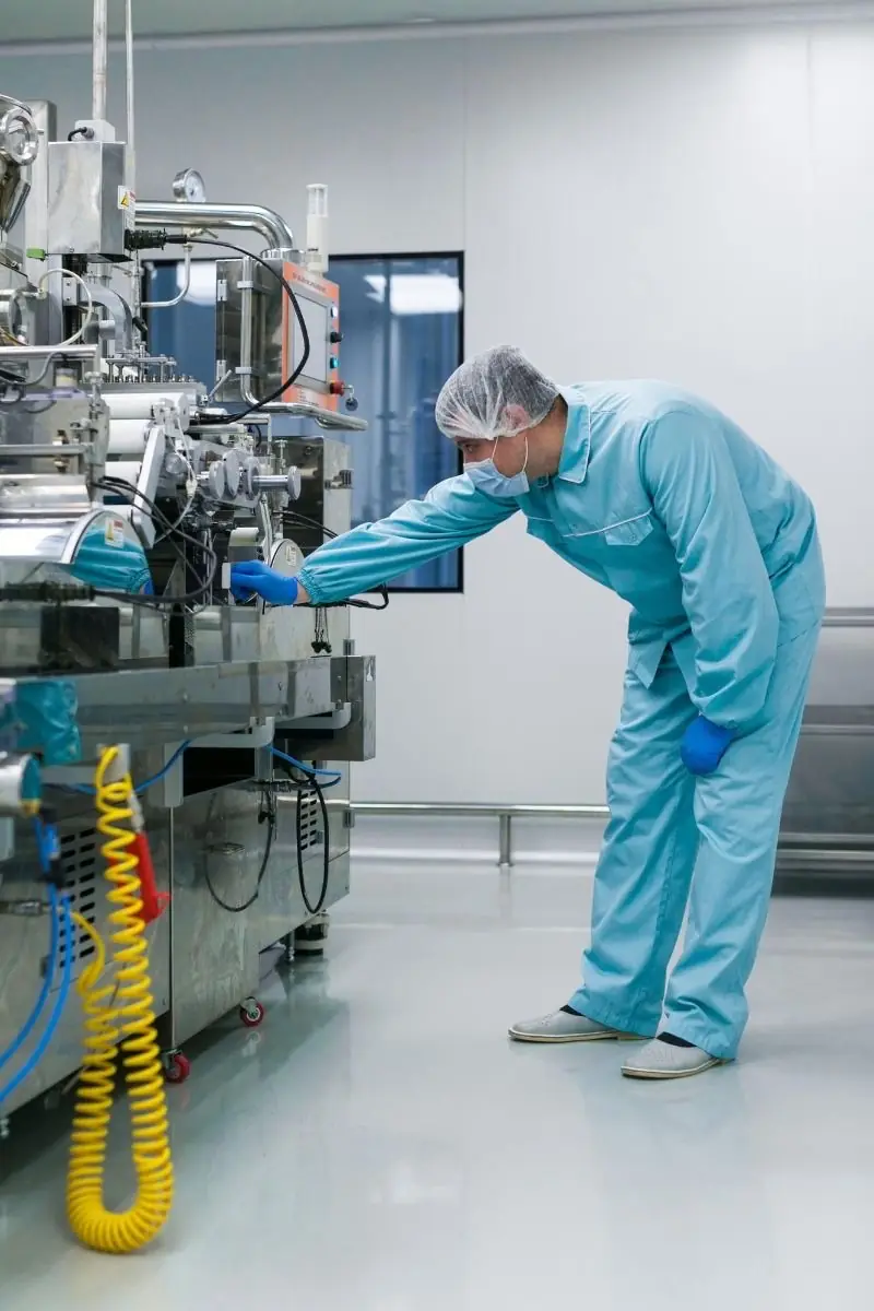 Technician checking equipment in a pharmaceutical cleanroom