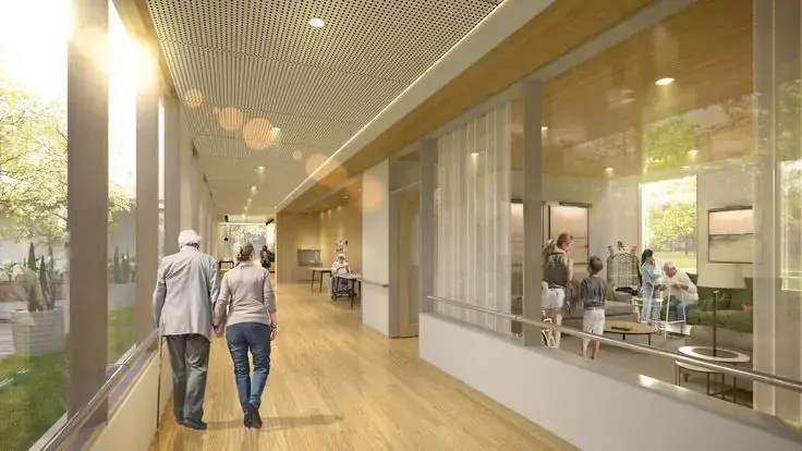 Elderly couple walking down a sunlit corridor in a care facility