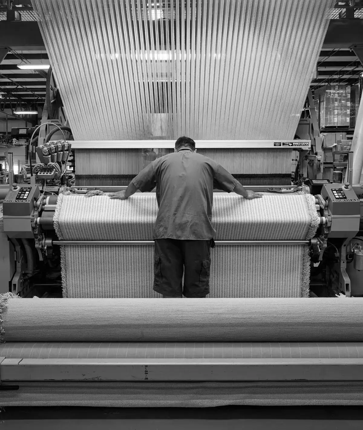 Worker at an industrial loom weaving fabric
