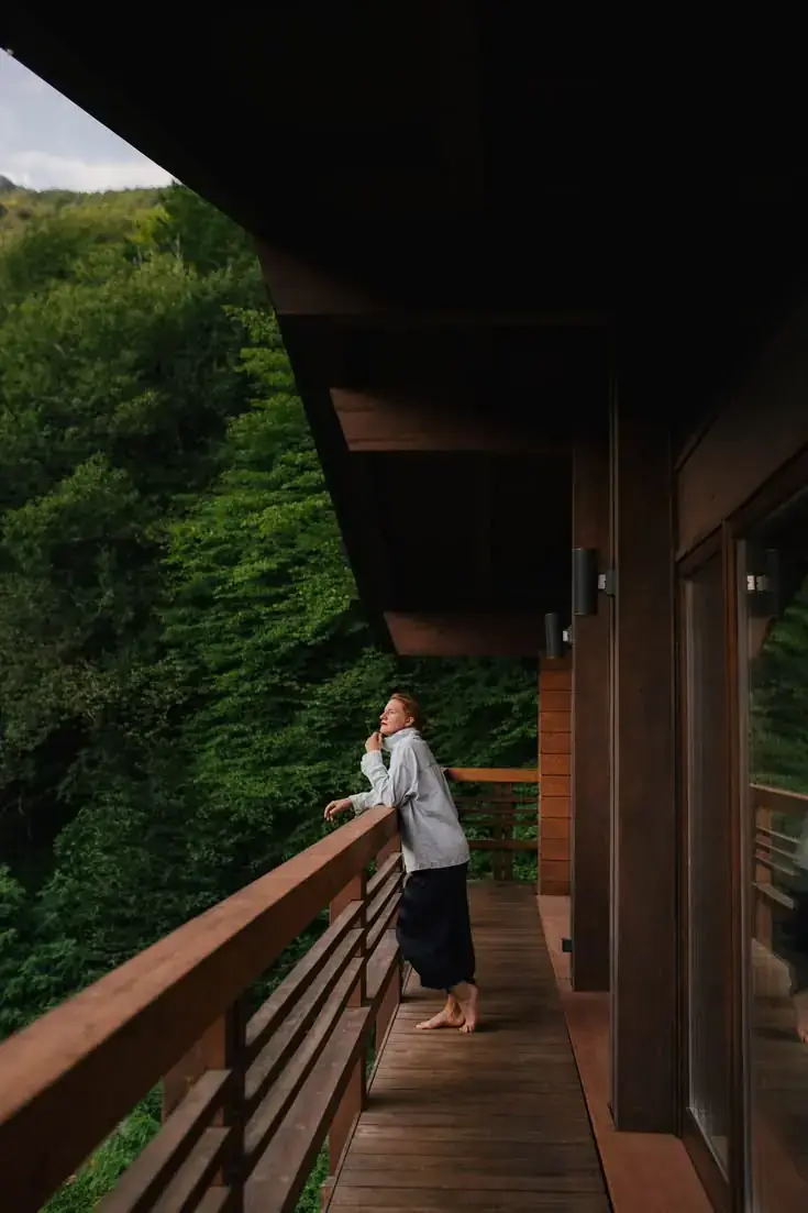 Guest relaxing on a wooden balcony overlooking a forest