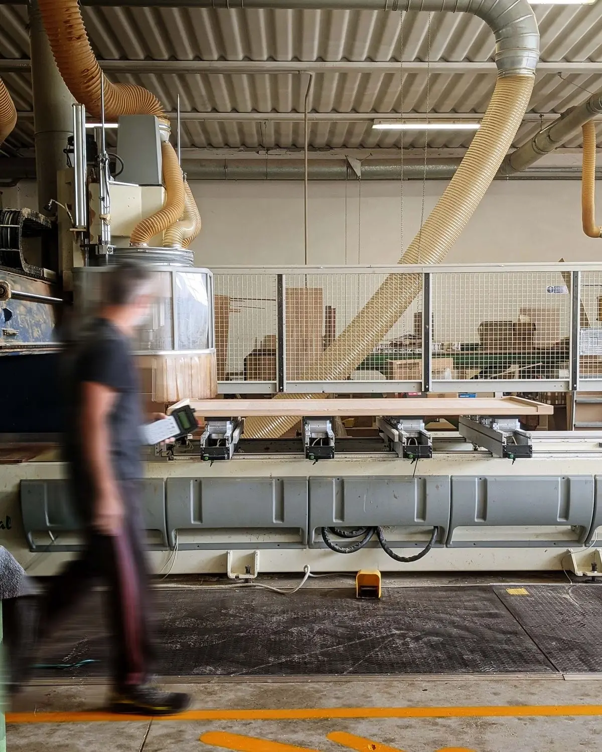 Operator walking past a CNC machine in a woodworking factory
